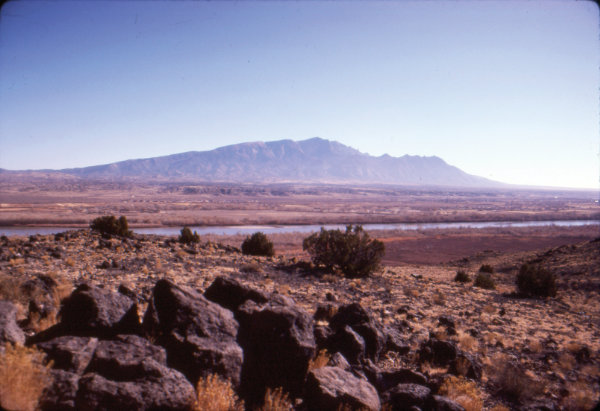 Figure 8: Rio Grande rift: Sandia Mountains and Rio Grande viewed from Bernalillo, New Mexico. The Sandia mountains are called fault-block mountains. The entire range has been lifted up along the eastern marginal faults of the Rio Grande rift, as the rift formed, and the rocks have tilted toward the east like an open trap door. The river took advantage of the low regions of the rift as it developed into a major waterway between one and four million years ago. Photograph by Jayne C. Aubele, New Mexico Museum of Natural History and Science.