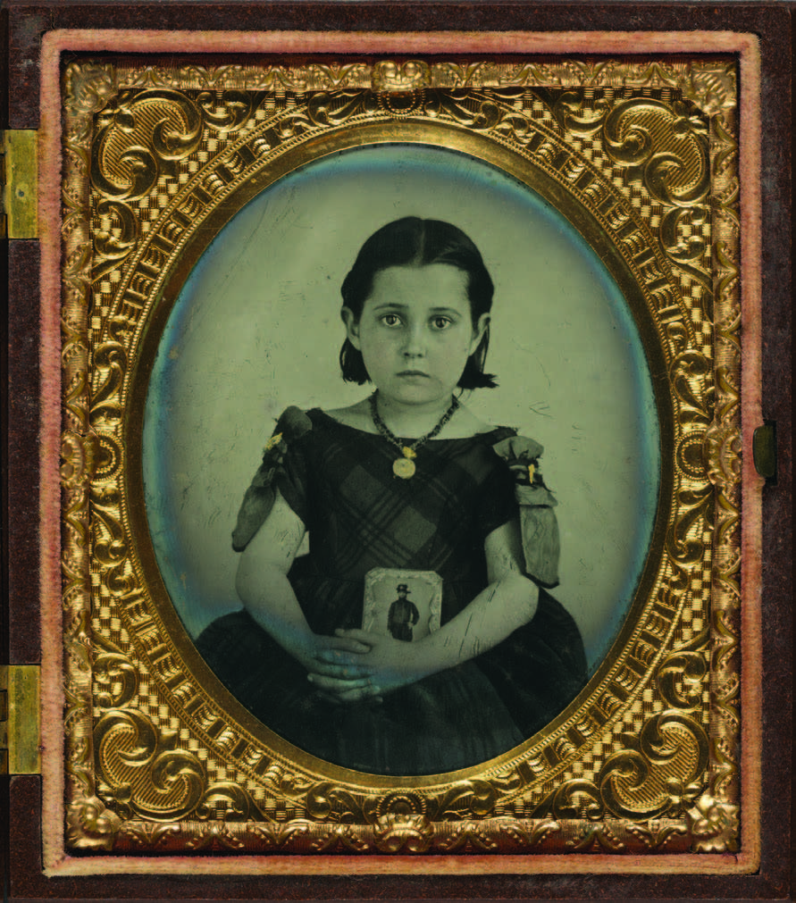 Unidentified girl in mourning dress, ca. 1861–1870. The girl holds a framed photograph of her father. Judging from her necklace, mourning ribbons, and dress, it is likely that her father was killed in the war. Courtesy of the Library of Congress.