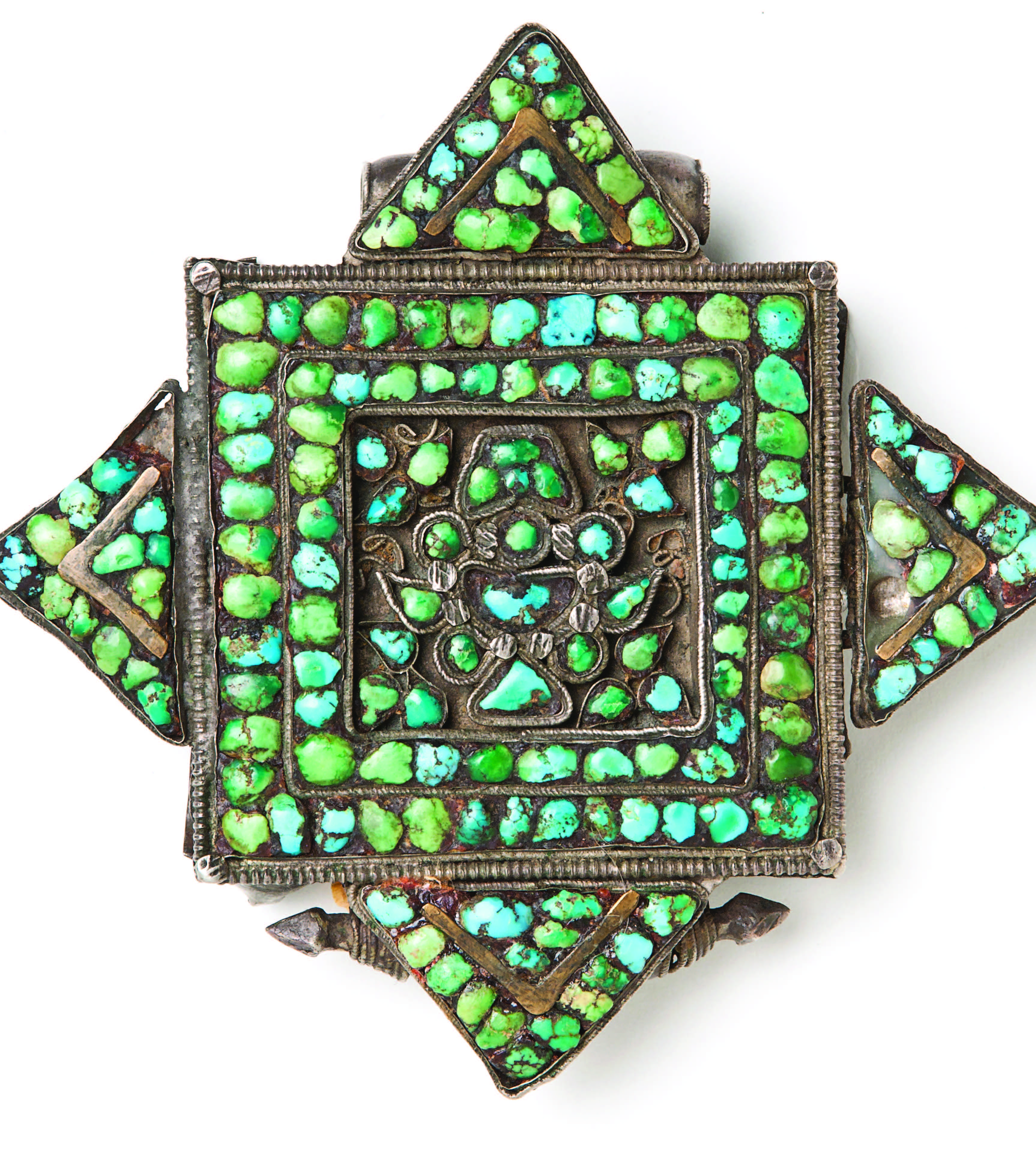 A common example of a ga’u, lavishly embellished with turquoise. The shape of this ga’u is known as a “double dorje.” A dorje (“diamond” or “thunderbolt”) is an important Buddhist symbol connoting the indestructibility and overwhelming power of the Buddha’s spiritual awareness. Paired with a bell, the dorje is one of the most important ritual tools of Tantric Buddhism. A double dorje is two crossed dorjes. In the center of the inner square, turquoise chips form one of eight auspicious Buddhist symbols, a treasure vase, or bum-pa. The bum-pa represents longevity and fulfillment of the highest aspirations. Silver, brass, turquoise, wax. Central Tibet, early to mid twentieth century. Museum of International Folk Art, gift of the Honorable Dorothy Brett (A.1960.12.1). Photograph by Blair Clark.