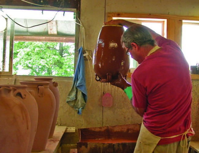 Ellington glazing a jar in the alkaline glaze he learned from Burlon Craig. The glaze consists of wood ash, crushed glass, and clay slip. Vale, North Carolina, 2013. Photograph courtesy of Kim Ellington.