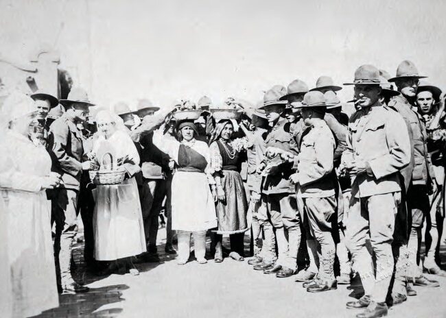 The Red Cross and Native American women giving “the boys” fruit, cigarettes, and handkerchiefs, ca. 1918. Courtesy of the Center for Southwest Research, UNM, Number 000-885(8)-0012.