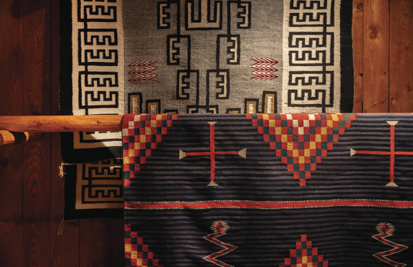 Foreground: Unknown artist (Navajo), Hubbell Trading Post rug, ca. 1800-1890. Commercial Germantown wool. 81 7 8 × 62 inches. Gift of Mr. and Mrs. Edward H. Tatum. MIAC Collection: 36197/12. Background: Unknown artist (Navajo), Two Grey Hills rug, ca. 1910-1920. Handspun wool, aniline dye. 88 3 5 × 54 ¾ inches. Gift of the Santa Fe Opera. MIAC Collection: 56595/12.