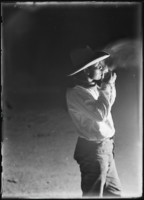 Erwin E. Smith (1886–1947), Cowboy lighting a hand-rolled cigarette making a smoke that looks like a brush-fire. A typical manner of smoking on the range in those days. JA Ranch, Texas., 1908. Gelatin dry plate negative. 7 × 5 in. Erwin E. Smith Collection of the Library of Congress on Deposit at the Amon Carter Museum of American Art, Fort Worth, Texas, LC.S6.917.