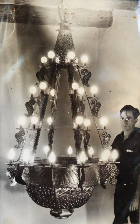 Robert Woodman standing next to newly completed terneplate chandelier fabricated for Our Lady of Carmel Catholic church in Montecito, California, built 1936–1938. Private collection.