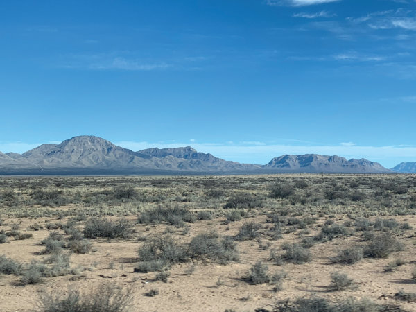 To get to Trinity Site, the convoy travels through Mockingbird Gap, a pass between the San Andres and Oscura mountain ranges. Mockingbird Gap is narrowest as it skirts past the Little Burro Mountains (pictured). The foreground of high desert scrubland, dominated by loose sandy soil and gnarled creosote, is typical of most of the missile range. Photograph by Andrew Wice.