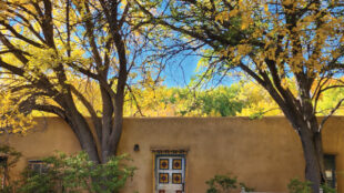 An eastern view of the almacén, featuring one of the two Folk Territorial doors that were added to the structure by Mary Cabot Wheelwright and Caroline Pfaffle in the early twentieth century.