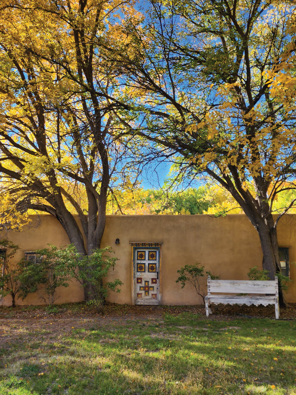 An eastern view of the almacén, featuring one of the two Folk Territorial doors that were added to the structure by Mary Cabot Wheelwright and Caroline Pfaffle in the early twentieth century.