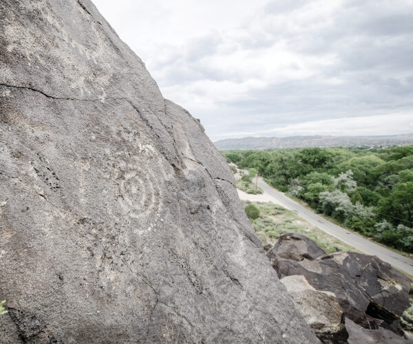 Petroglyphs of a war club, concentric circles, and a partial human figure on the lower right overlook the northern Rio Grande Valley on Mesa Prieta.