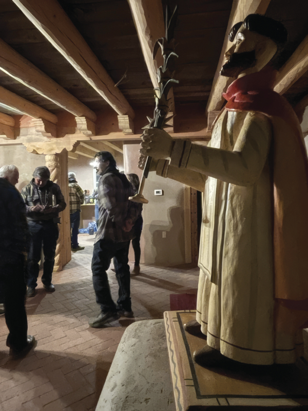 Guests and wooden bulto of San Ramon (by santero Alacrio Otero),
Tomé, New Mexico, 2023. Capilla San Ramón. Photo by Leanna Torres.